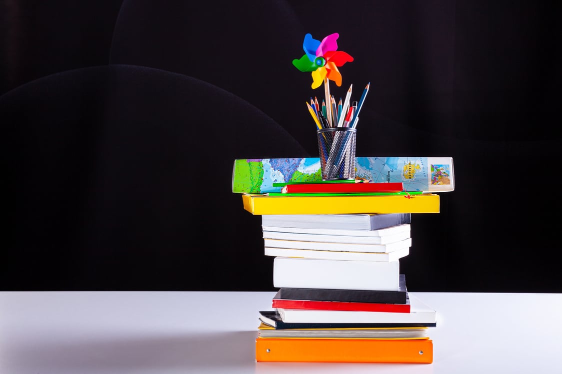 Pinwheel and pencils pot on stacked books, school supplies o